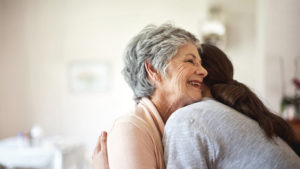 adult daughter hugging older mother