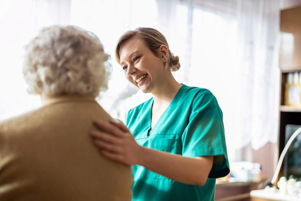a nurse with a Senior Health Care Career helps a senior in a bed