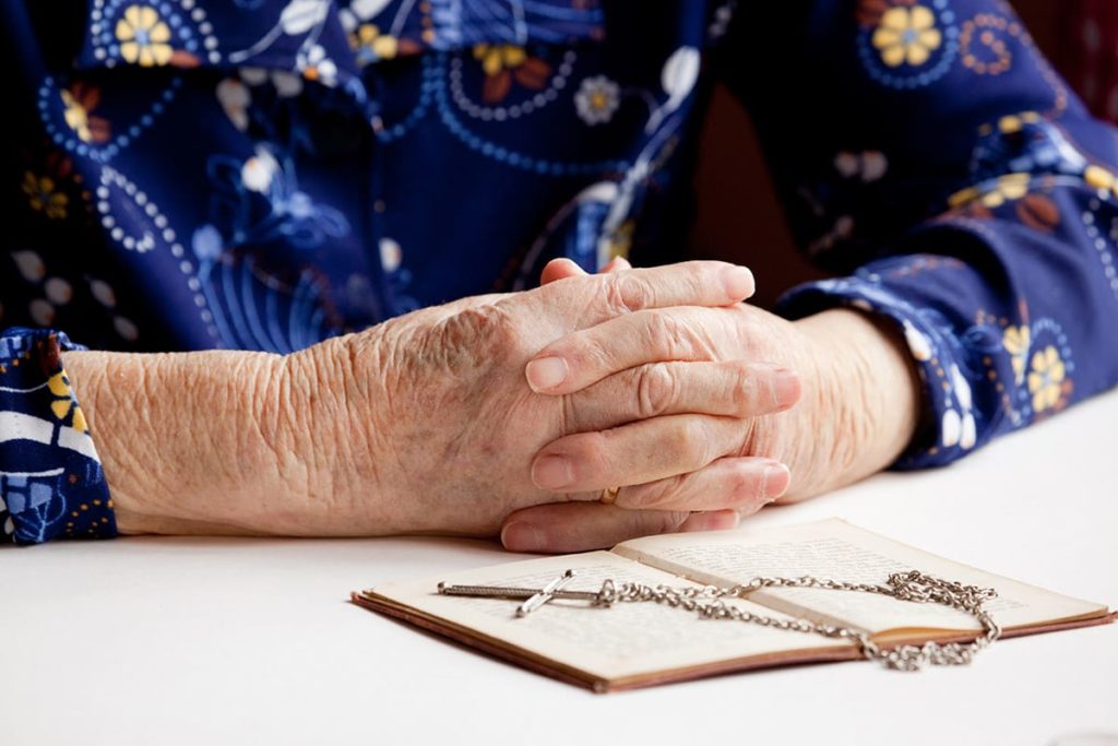 Person with folded hands in prayer reaping the benefits of a chaplaincy program
