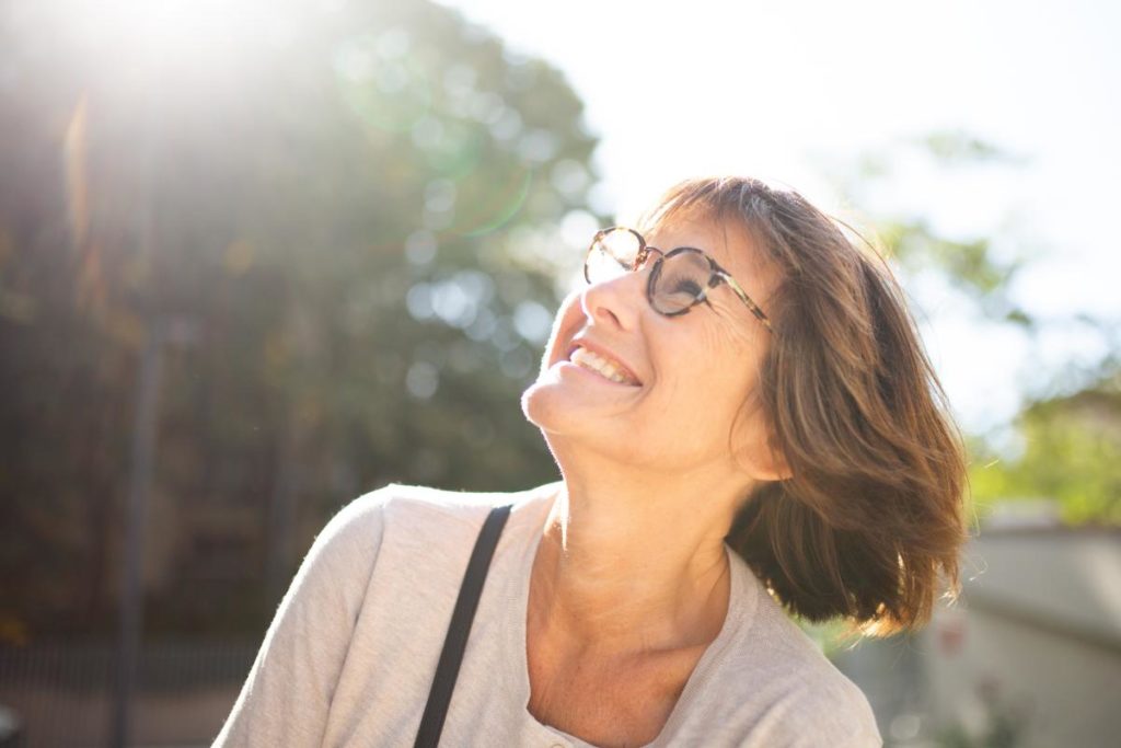 Happy senior woman enjoying sunshine outdoors while considering memory care length of stay