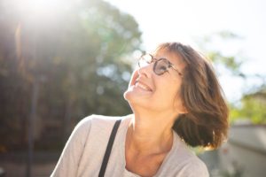 Happy senior woman enjoying sunshine outdoors while considering memory care length of stay