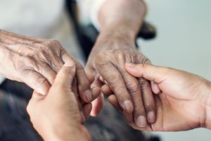 Caregiver taking a patient's hands while discussing length of stay in skilled nursing care