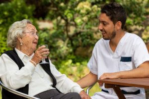 Happy caretaker talking to senior woman in assisted living after undergoing memory care professional trainings