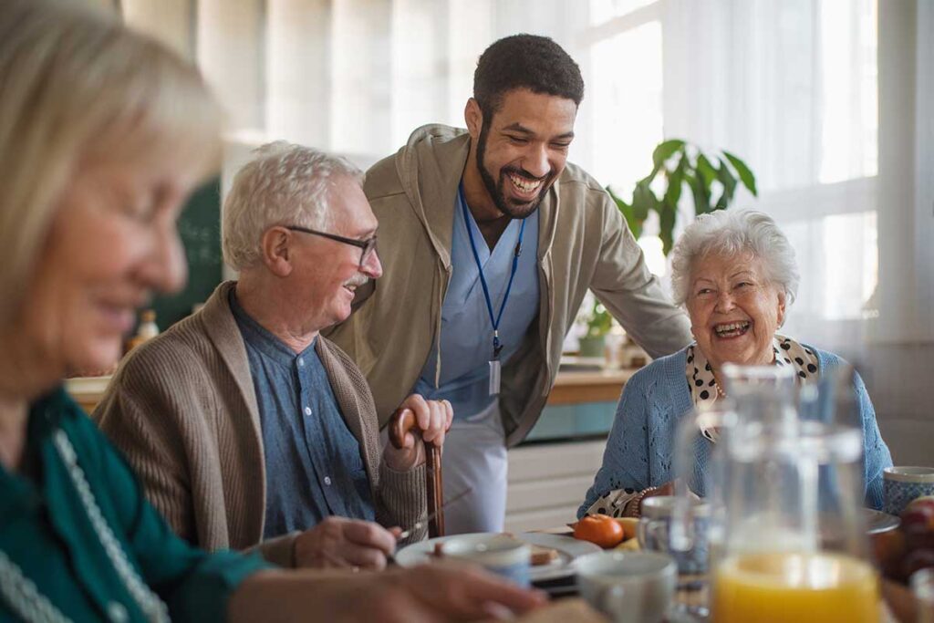 people enjoying a meal while talking to a smiling caregiver after finding assisted living in austin tx