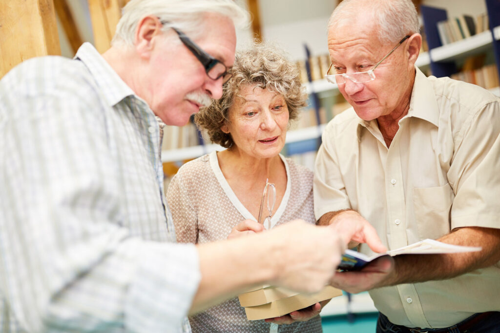 group of seniors browsing catalog of educational programs in senior living